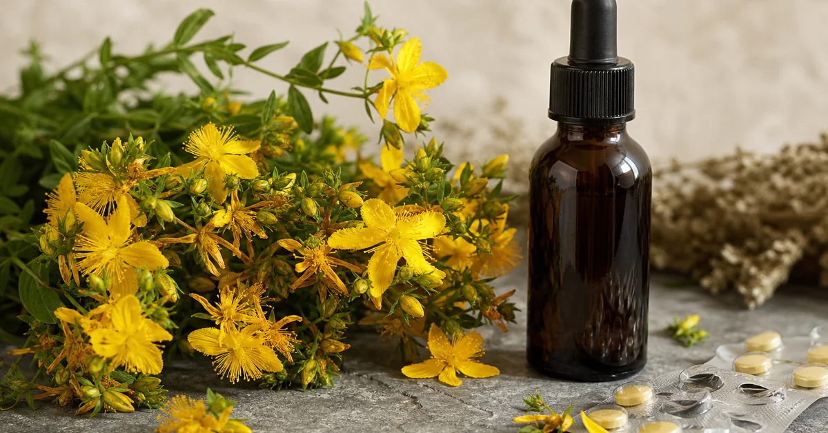 Blühendes Johanniskraut mit gelben Blüten neben Tabletten und einer Braunglasflasche